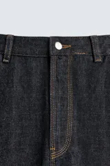 Jeans de hombre relaxed straight fit, color azul oscuro, confeccionados en denim rígido sin prelavados. Presentan cinco bolsillos, bolsillos plastrón y tira multifunción en las perneras. Cierre frontal con cremallera y botón.