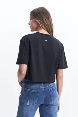 Remera corta (cropped) de algodón color verde lima, con cuello redondo y manga corta. Presenta un pequeño estampado en el pecho con un corazón naranja y texto manuscrito.