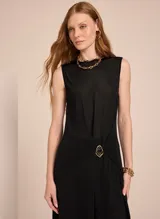 Túnica negra sin mangas de tricot con escote redondo, detalle de broche dorado superpuesto y aberturas laterales.