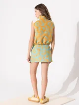 Minifalda celeste con estampado de flores amarillas, tiro bajo, bolsillos frontales y cierre con cremallera.