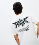 Remera de algodón con cuello redondo y manga corta. Presenta un diseño con estampa pequeña en el pecho y un gráfico estilo graffiti en la espalda.