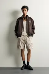 Bermuda cargo color negro de corte relaxed fit, confeccionada en tejido de algodón con elasticidad y efecto lavado. Cuenta con cintura elástica ajustable con cordón, bolsillos frontales y bolsillos laterales tipo cargo con solapa en las perneras.