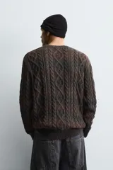 Jersey de punto con diseño de trenzas, cuello redondo y manga larga. Presenta un acabado en rib en puños y ruedo, con un efecto de lavado que le otorga una apariencia única.