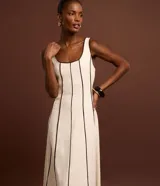 Vestido largo evasê sin mangas de color beige, con escote cuadrado y costuras verticales con bies en tono contrastante oscuro.