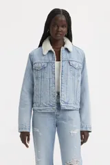 Campera de jean celeste claro con cuello de piel sintética blanca, bolsillos frontales con solapa y cierre con botones metálicos.