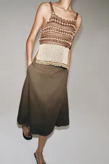 Top de crochet con escote recto y tirantes finos. Presenta un diseño bicolor con la parte superior en color marrón y la parte inferior decorada con abalorios en tonos crema y marrón.