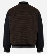 Campera bomber de estilo college con cuerpo a cuadros en tonos marrones y mangas largas de cuero sintético negro. Presenta cuello, puños y cintura acanalados a rayas, cierre abotonado, bolsillos laterales y aplique bordado de letra "B" en el pecho.