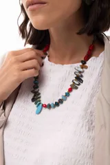 Collar corto de diseño artesanal compuesto por una variedad de cuentas de piedras naturales, cristales checos y acrílicos en tonos multicolor, incluyendo rojo, azul, turquesa y gris. Presenta un dije central en forma de gota color turquesa y cierre con cadena de acero quirúrgico ajustable.