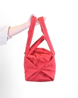 Bolso tipo tote color beige con diseño acolchado y doble asa de hombro.