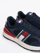 Zapatillas Tommy Jeans de corte bajo, color azul marino con detalles en rojo y blanco. Capellada de ante y malla, con logo de la marca en el lateral y suela de goma dentada.