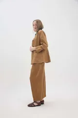 Pantalón de lino marrón de tiro medio, con calce holgado y diseño de piernas amplias. Cuenta con bolsillos traseros, trabillas para cinto y un pin bordado en contraste.