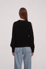 Sweater negro de algodón con cuello redondo y mangas largas con aberturas en los hombros.