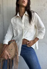 Camisa de lino color natural, con cuello clásico, mangas largas y detalles de encaje bordado en el frente.