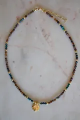 Collar corto de cuentas facetadas de crisocola y pietersita en tonos tierra, azul y verde, con esferas doradas intercaladas y un dije redondo dorado con diseño de estrellas y pequeños cristales.