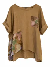 Blusa color camel de lino, con cuello redondo, mangas cortas con vuelta y detalles de tela estampada con diseño floral en el bolsillo del pecho y en un lateral.