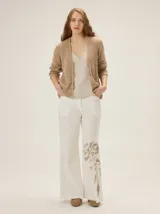 Cardigan de punto color blanco marfil, con escote en V, mangas largas con detalles de tejido calado y cierre frontal de botones con efecto madera.