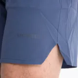 Short deportivo azul con cintura elástica y cordón interior, calzoncillo interior, bolsillos delanteros y bolsillo trasero con cierre invertido. Estampados reflectivos a tono.