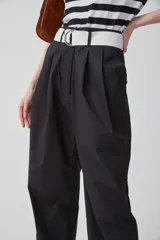 Pantalón negro de gabardina liviana de algodón, tiro alto con pinzas delanteras, bolsillos americanos y cierre metálico.