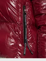 Campera corta acolchada de plumas, con acabado brillante. Presenta un diseño bicolor: exterior en color borgoña/vino y forro interior en rosa pálido. Tiene capucha y cierre frontal.