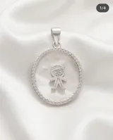 Dije circular de plata 925 con centro de nácar, borde engastado en circonias y figura central de niño con detalles en circonias.