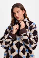 Campera de corderito sintético con diseño a cuadros en tonos marrones y negros. Presenta cuello alto, cierre frontal completo y detalles de paneles en color marrón liso. El diseño es de silueta holgada, largo tipo crop y cuenta con un cordón elástico ajustable en el ruedo.