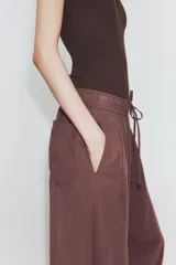 Pantalón de tiro medio con corte estilo balloon, cintura elástica ajustable con cordones, bolsillos laterales ocultos y bolsillos de plastrón en la parte trasera.