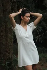 Vestido corto color blanco hueso, de lino con mezcla, corte evasé, cuello en V y botones de nácar.