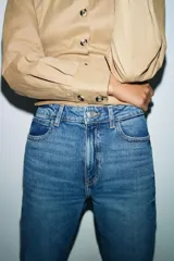 Jeans de tiro alto con corte mom fit, diseño de cinco bolsillos y raya planchada frontal. Presenta cierre frontal con cremallera y botón.