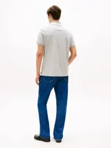 Chomba gris de corte regular confeccionada en tejido interlock de algodón suave. Cuenta con cuello de chomba, billetera de dos botones, raya a contraste en el cuello y logo del monotipo Hilfiger bordado en el pecho.