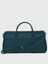 Bolso tipo shoulder bag de diseño minimalista y estructurado, confeccionado en cuero liso color azul petróleo. Cuenta con doble asa superior, correa de hombro ajustable y extraíble, y cierre superior con cremallera.