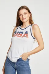 Musculosa blanca con cuello y sisas ribeteadas en azul marino. Estampado frontal con la palabra "USA" en letras rojas con rayas horizontales azules.