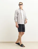 Camisa de lino a rayas verticales color beige y blanco, de corte clásico, con cuello abotonado y mangas largas.