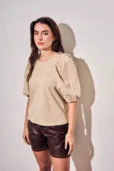 Remera de algodón negro con mangas cortas abullonadas, cuello redondo y costura central frontal.