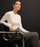Suéter de punto color blanco con cuello redondo y mangas largas. Presenta una textura geométrica de losangos en toda la prenda y un corte ajustado al cuerpo.