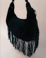 Cartera tipo hobo de gamuza color beige, con diseño amplio y detalle de flecos largos en todo el contorno. Cuenta con un asa superior con pespuntes artesanales y cierre principal.