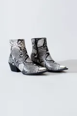 Bota texana corta con estampado de piel de serpiente en tonos blanco y negro, puntera metálica plateada, cierre lateral y taco bajo.