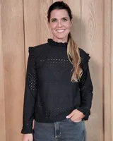 Polera de manga larga confeccionada en tela broderie negra, con cuello alto con volados y detalles de volados en los hombros.