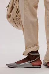 Zapato plano negro de cuero, tipo chatita, con punta fina y tiras con hebilla ajustable alrededor del tobillo.