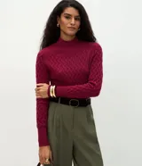 Suéter de punto color fucsia con textura de zigzag, cuello alto y mangas largas ajustadas con puños acanalados.