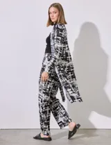 Cardigan largo de satén plisado con estampado abstracto en blanco y negro, marca Cyrus. Presenta aberturas laterales.