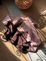 Buzo de polar tipo corderito con diseño de bloques de color en tonos rosa y marrón chocolate. Presenta cuello alto con cierre frontal parcial y un aplique circular en el pecho.