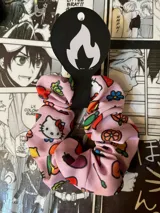Scrunchie de tela rosa con estampado de Hello Kitty y frutas.