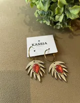 Aros colgantes con gancho dorado y dije con forma de hoja plateada con centro de piedra roja.