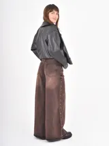 Jean de corte wide leg en color óxido con efecto lavado. Presenta una abertura lateral decorada con pequeñas tachas metálicas a lo largo de toda la pierna.