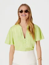 Blusa verde con estampado geométrico blanco, cuello en V y mangas cortas amplias.