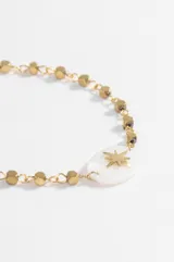 Pulsera dorada de acero quirúrgico con dije central ovalado de nácar blanco con una estrella dorada grabada. La cadena presenta eslabones intercalados con cuentas facetadas.