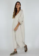 Vestido largo color crudo, de corte holgado, escote en V y mangas largas.