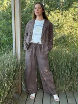 Pantalón de corte ancho y relajado, confeccionado en lino con diseño de rayas verticales. Presenta cintura elástica con cordón de ajuste y bolsillos laterales.