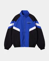 Campera deportiva de diseño colorblock en tonos azul, negro y blanco, con cierre frontal y cuello alto. Presenta detalles de franjas y un pequeño estampado en el pecho con la inscripción "Uruguay Run Club".
