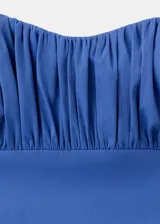 Vestido midi azul sin tirantes, con escote palabra de honor fruncido en el pecho, corte ajustado en el torso y falda amplia de corte evasé.